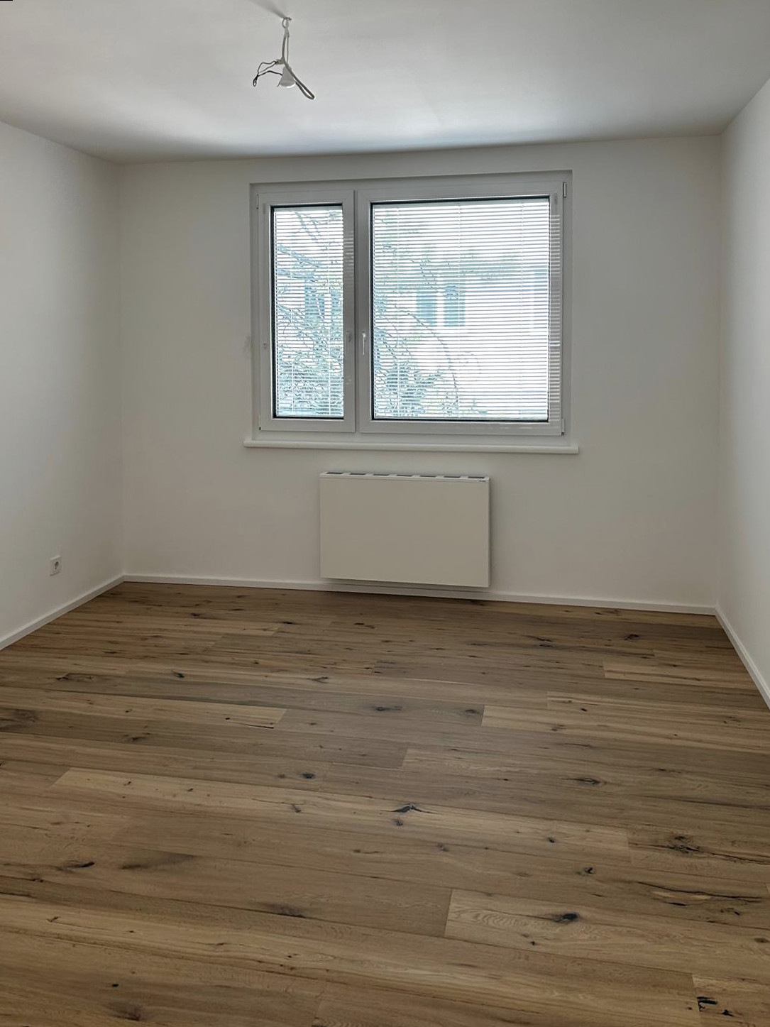Zweites Zimmer mit neuem Holzboden und Fenster zum Garten