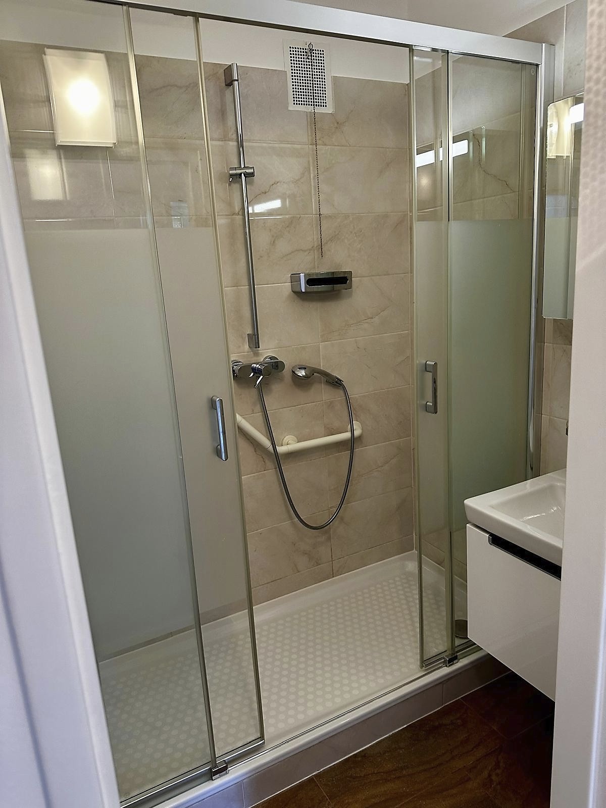 Badezimmer mit Duschkabine und Marmoroptik-Fliesen