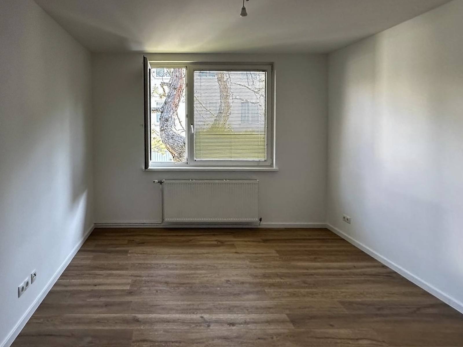 Zimmer mit Holzboden und Fenster zum Garten